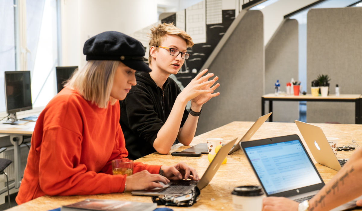 Foto av to studenter som sitter rundt et bord og diskuterer
