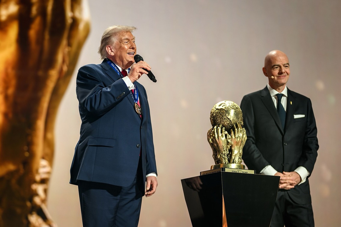 Donald Trump snakker i en mikrofon på scenen med FIFA-president Gianni Infantino