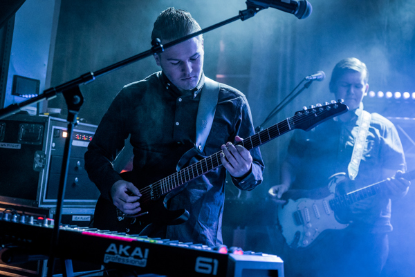 Bilde av gitarist på scene med blått stemningslys.