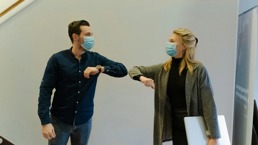 Two people with facemasks giving each other an elbow bump