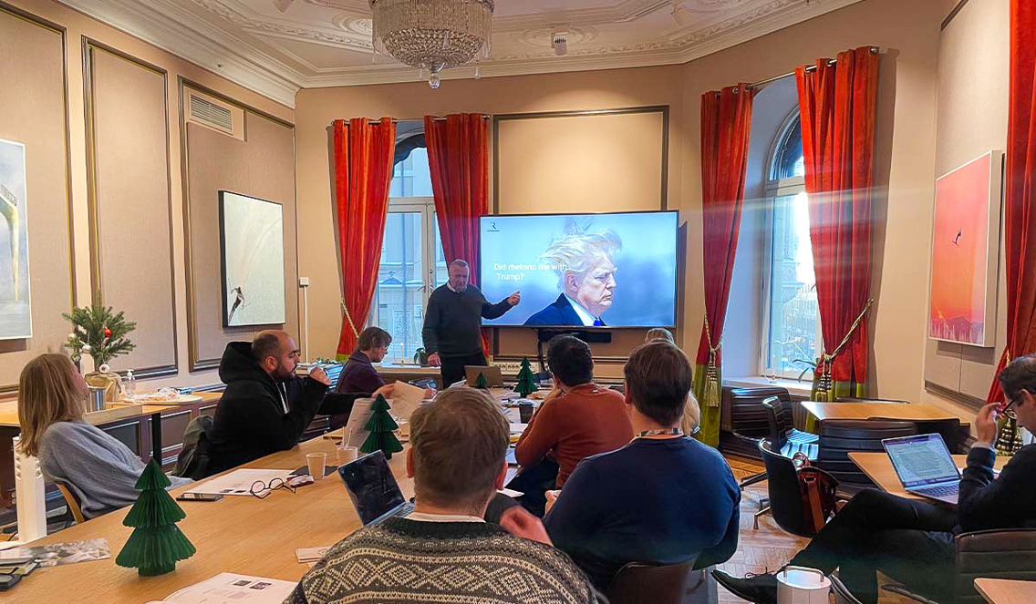 Kjell Terje Ringdal står foran en skjerm med bilde av Donald Trump mens han gestikulerer til studentene som ser på. Foto.