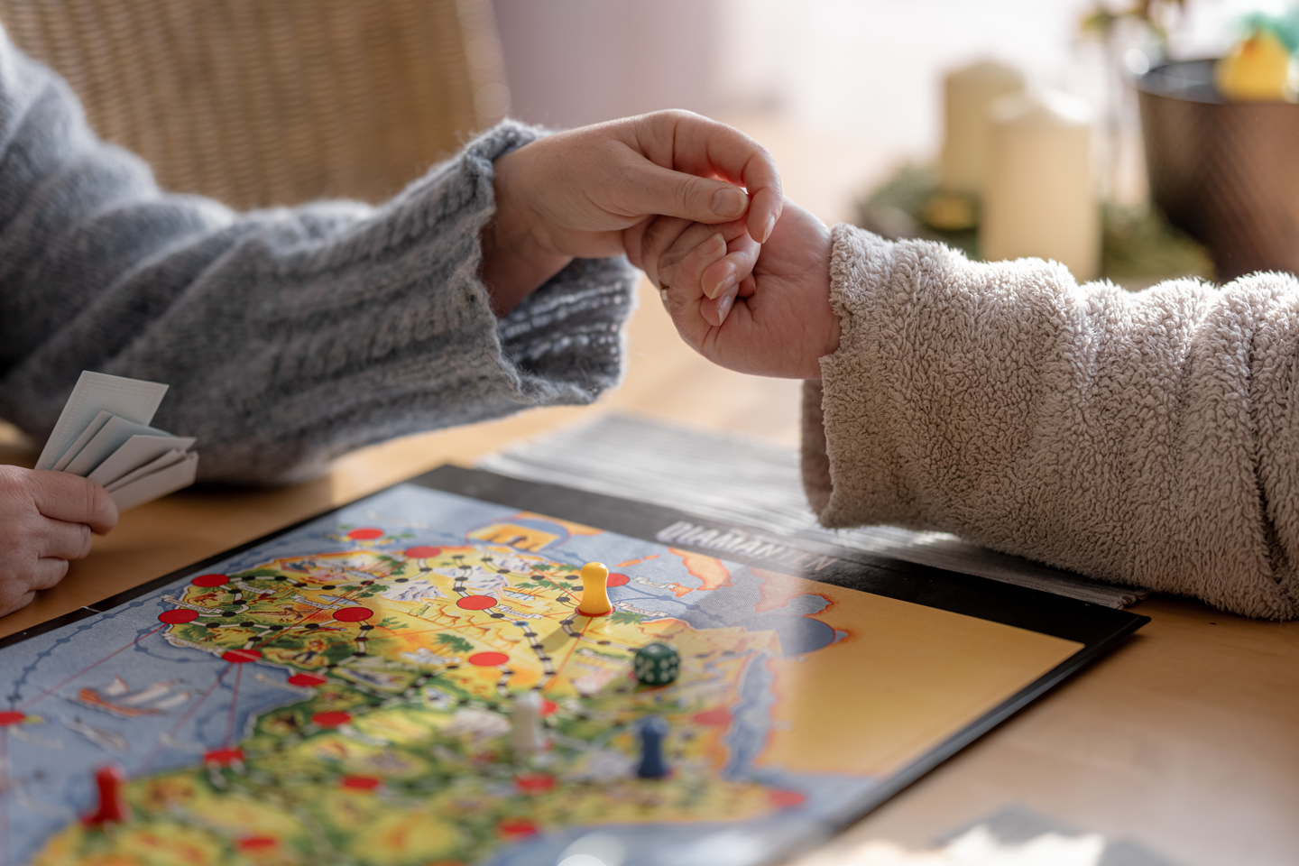 To hender holder sammen over et bord med brettspill