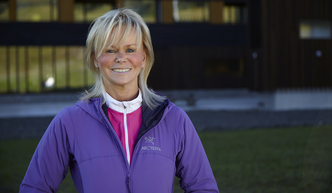 Elin Bolann står i en lilla sportsjakke med en rosa og hvit ullundertøy-genser under. Hun har kort blondt hår med pannelugg. Hun smiler bredt og er rosa i kinnene. 