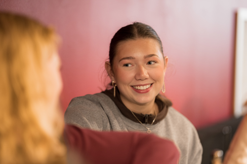 Student smiler og er i samtale med en annen medstudent