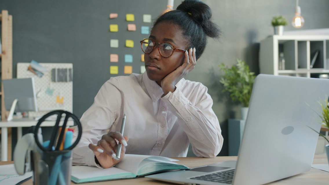 Woman sitting with post-it notes on her wall in front of her tv thinking