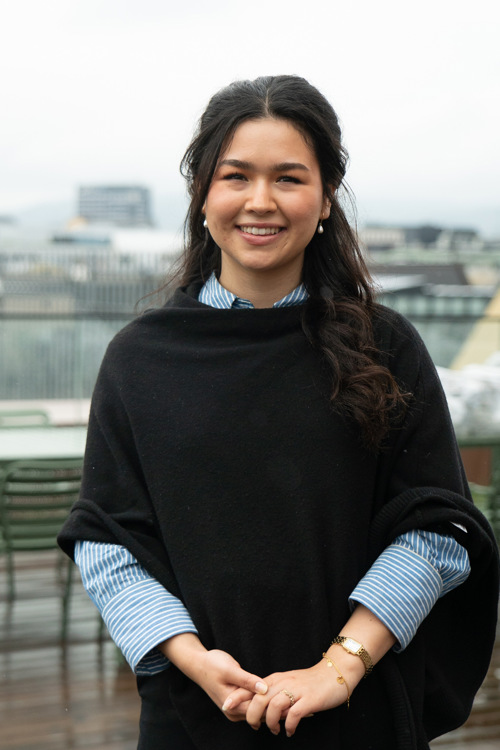 Zahra står på takterrassen på Campus Kristiania i Kirkegata, med bygningen i bakgrunnen.