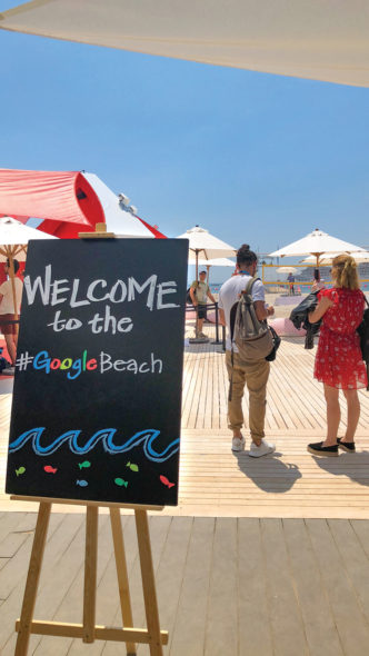 Et skilt der det står "Welcome to the #GoogleBeach" med en strand og parasoller i bakgrunnen