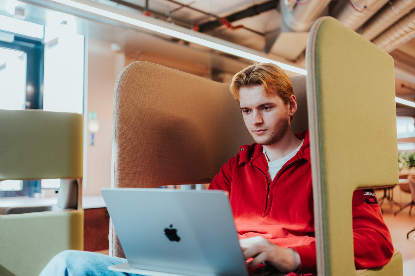 Student jobber med PC i en stol designet for å dempe romlyd.