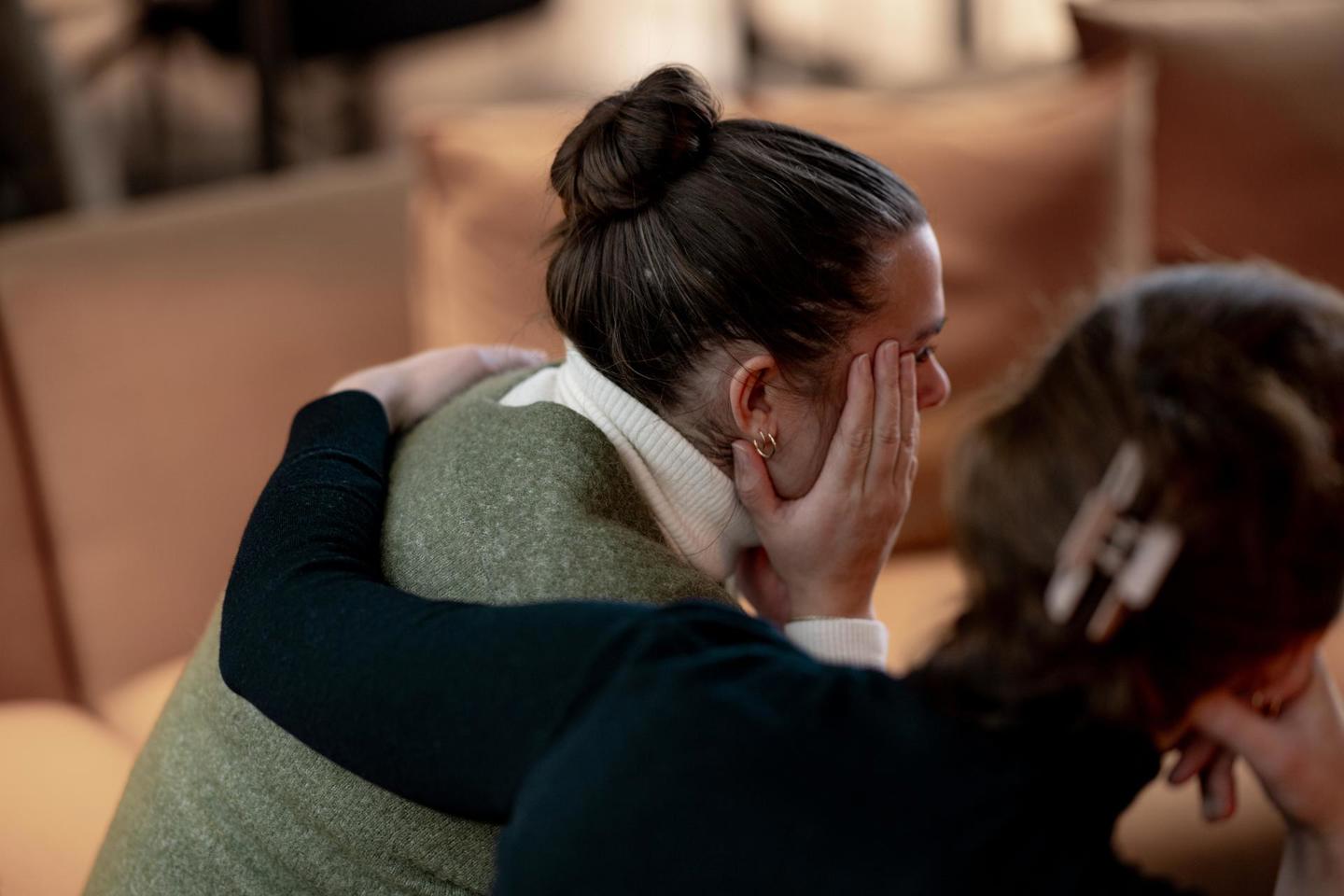 To personer sitter tett sammen i en sofagruppe, der den ene holder rundt den andre