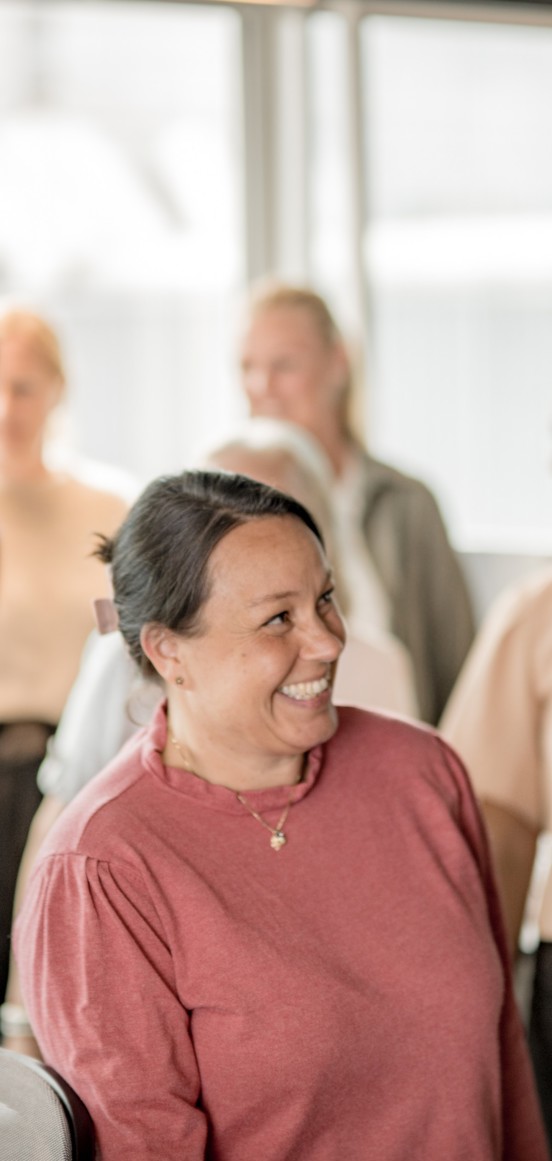 Fagansvarlig smiler til andre kollegaer i et lyst kontormiljø