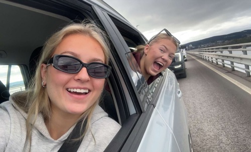 To personer smiler til kamera fra en bil