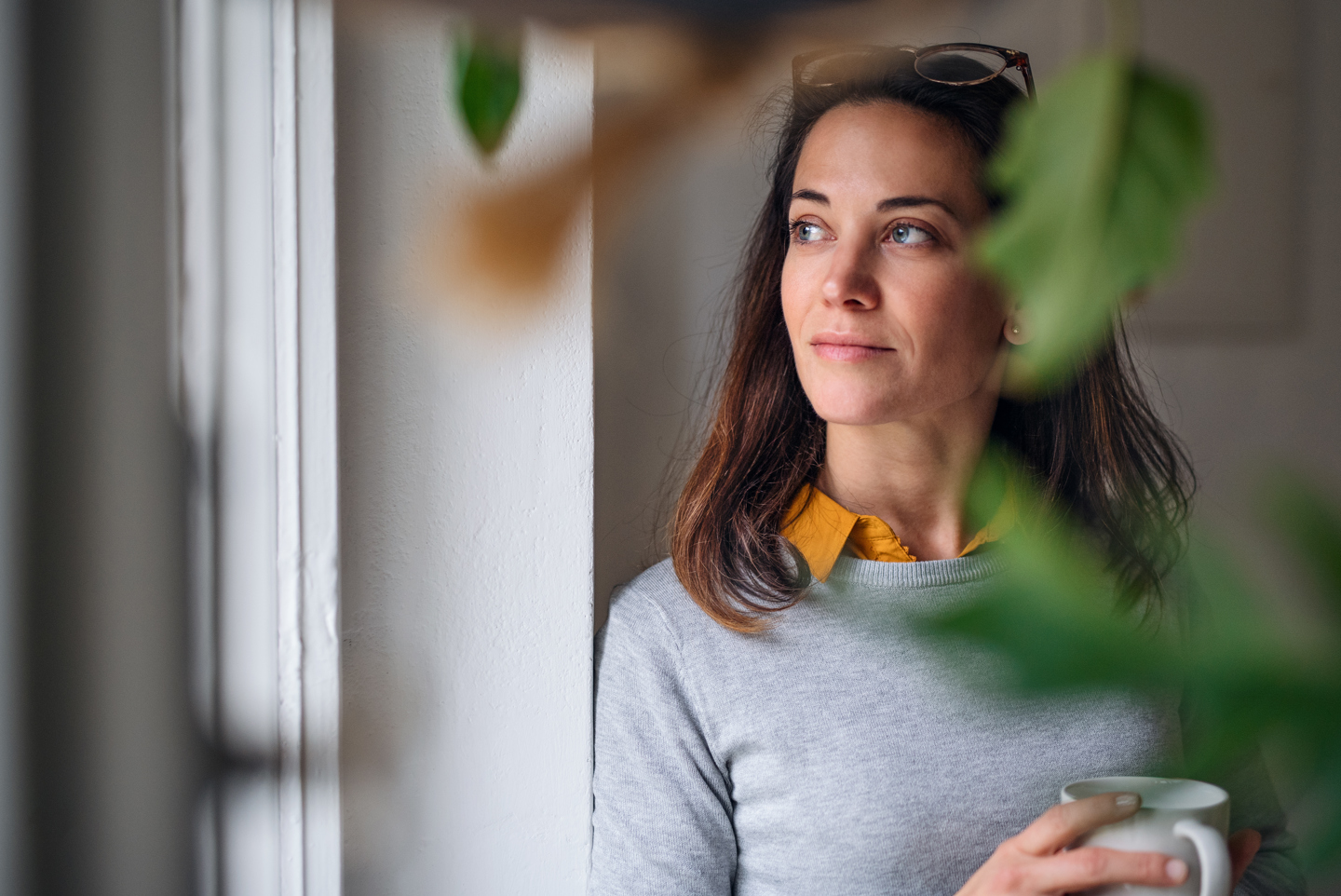Dame holder kopp og ser ut av vinduet