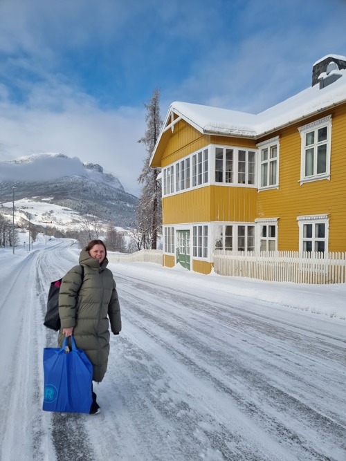 Person går på snødekt vei foran gult bygg i Valdres, fra praksisprosjekt på sommerhotell