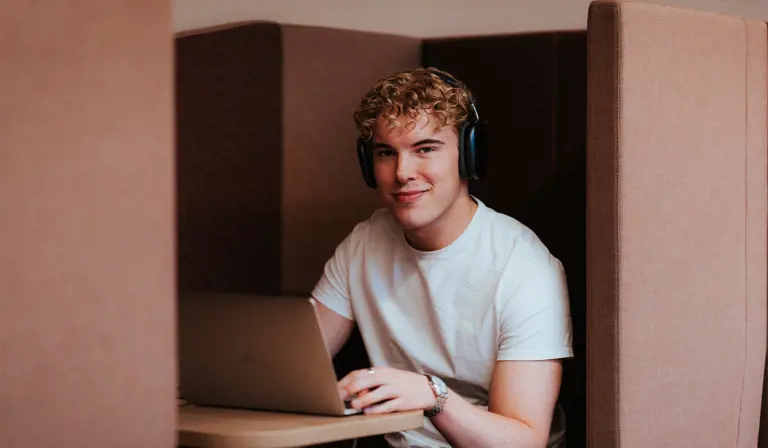 Student som følger nettstudier ved hjelp av bærbar PC og hodetelefoner.
