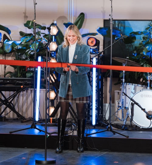 En dame i skjørt og blaser klipper over en snor. 