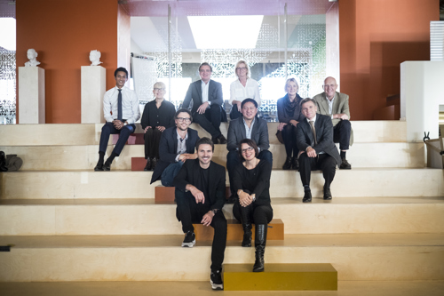 Flere kvinner og menn sitter i en trapp og smiler. 