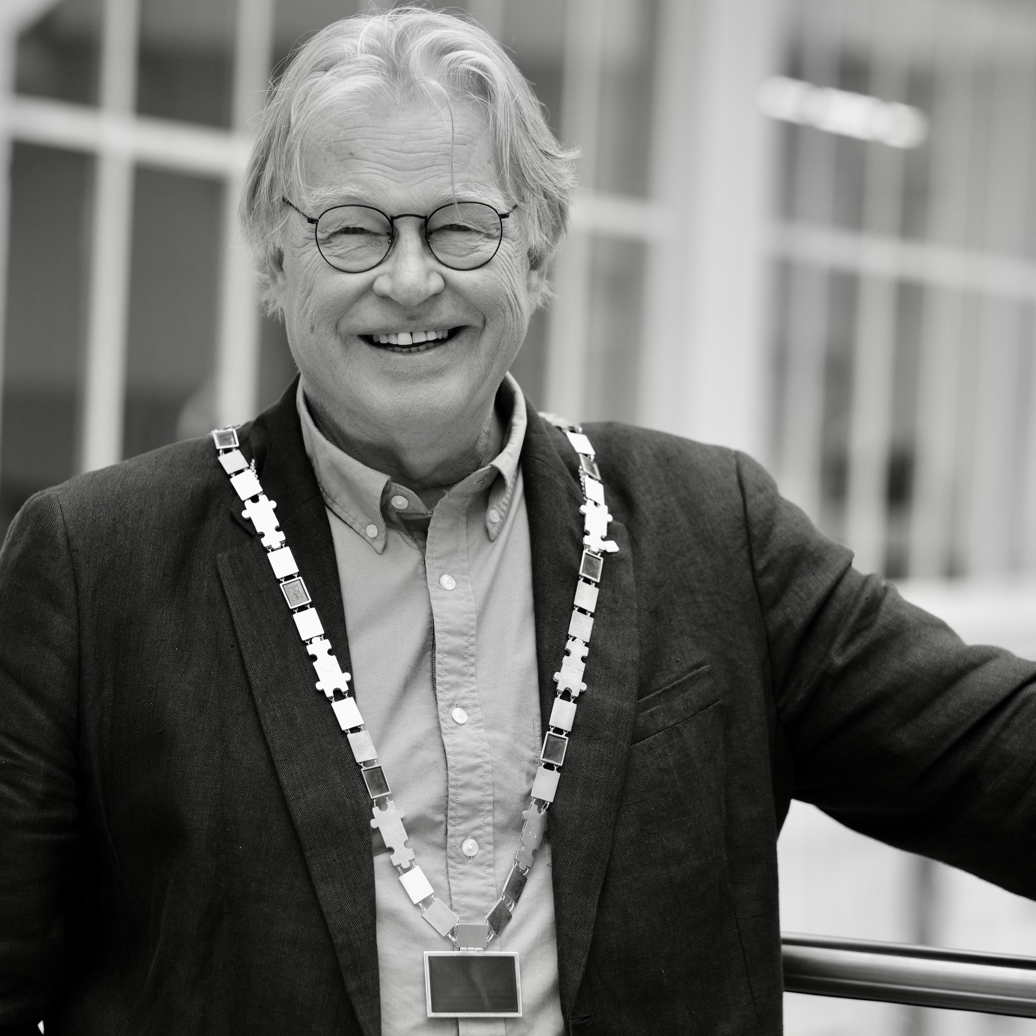 Smilende mann med briller og dress, og et stort rektorkjede rundt halsen